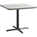 A Lancaster Table & Seating white birch table top with a white and black base on a table.