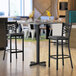 A Lancaster Table & Seating bar height table with a white top and black base set.