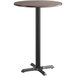 A round bar table with a Lancaster Table & Seating black base and a reversible wood top with white birch and ash finishes.