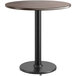 A Lancaster Table & Seating round table with a black pole and a reversible wood top.