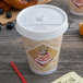 A Dart white plastic sip thru lid on a coffee cup with donuts.