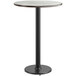 A round bar height table with a white birch and ash striped top on a black base.