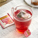A glass mug of Twinings Heartea+ Raspberry Hibiscus tea with a tea bag in it.