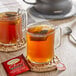 Two glass mugs of Twinings Chai decaffeinated tea with tea bags on a table.