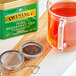 A tea cup and strainer filled with Twinings Irish Breakfast tea next to a tin of Twinings Irish Breakfast tea.