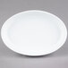 A white oval porcelain serving platter with a rim on a gray surface.