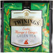 A green Twinings tea bag with a white label featuring birds and text for Green Exotic Mango & Ginger Tea.