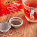 Loose leaves from Twinings English Breakfast Tea in a metal mesh strainer over a cup of tea.