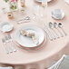 A table set with plates and silverware including Acopa Triumph stainless steel demitasse spoons.