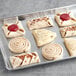 A tray of Schulstad pastries with different shapes and flavors on a gray surface.