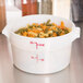 A white Cambro round food storage container filled with multicolored pasta.