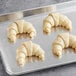 A Schulstad curved butter croissant on a metal tray.