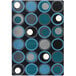 A close-up of a Joy Carpets rectangle area rug with blue, black, and grey circles on it.