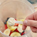 A hand holding a spoon of Add A Scoop protein powder with a scoop of powder and a banana.