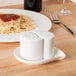 A plate of spaghetti with a CAC Bone White China salt and pepper shaker on the table.