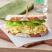 A sandwich with lettuce and Papetti's hard cooked eggs on a wooden cutting board.