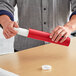 A person holding a Lavex red mailing tube over a table.