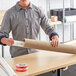 A man holding a Lavex Kraft cardboard tube on a table.