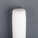 A 12" white Will & Baumer taper candle with a black tip on a gray surface.