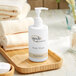 A white bottle of Novo Essentials body wash on a wooden tray with towels.