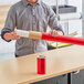 A person holding a red telescoping mailing tube.