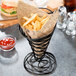 An American Metalcraft black wire birdnest basket filled with french fries and a side of ketchup.