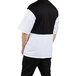 A man wearing a white Uncommon Chef Rogue Pro Vent chef coat with a black and white mesh back.