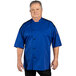A man wearing a royal blue Uncommon Chef short sleeve chef coat with mesh back.