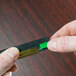 A person holding a small black and green rectangular squeegee blade.