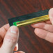 A person holding a green and black piece of metal with a rubber edge.