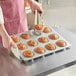 A person putting muffins in a Baker's Mark jumbo muffin pan.