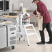 A man in a red shirt and apron using the Estella manual dough divider on a counter in a professional kitchen.