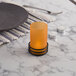 An orange frost cylinder globe candle holder on a table.