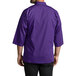 A person wearing a purple Uncommon Chef 3/4 length sleeve chef coat.