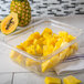 A Carlisle clear polycarbonate food pan drain tray with pineapple slices in it on a counter.