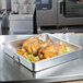 A Vollrath aluminum roasting pan with chicken and vegetables on a counter.