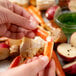 A hand holding a Chesapeake Crab Connection snow crab leg over a table with food on it.