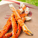 A pile of Chesapeake Crab Connection Alaskan King Crab legs on a brown paper bag.
