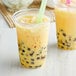 Two cups of Bossen mango bubble tea with green and pink straws.