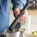 A man using an Acopa black stainless steel muddler with tenderizer head to make a cocktail.