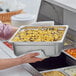 A person holding a Choice stainless steel tray of food.