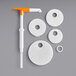 A white disc with a hole in it and a white and orange plastic tool with circles and a handle.