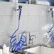 A Waterloo wall-mounted pet grooming faucet with a coiled blue hose and a faucet with blue hoses.
