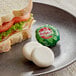 A sandwich on a plate with a Babybel vegan plant-based cheese wrapper.