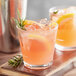 Two Acopa Select stackable rocks glasses filled with pink lemonade and garnished with rosemary and lemon slices.