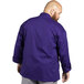 A man wearing a purple Uncommon Chef Orleans long sleeve chef coat.