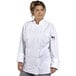 A woman wearing a Uncommon Chef white long sleeve chef coat with mesh back.