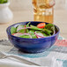 A bowl of salad with vegetables in an Acopa Capri deep sea cobalt bistro bowl.