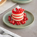 A stack of cake with berries and whipped cream on a sage matte coupe porcelain plate.