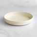 An Acopa Pangea fog white porcelain pasta bowl on a marble surface.